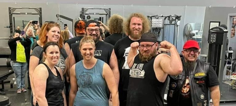 Josh posing with some of his clients in the gym he trains them at.