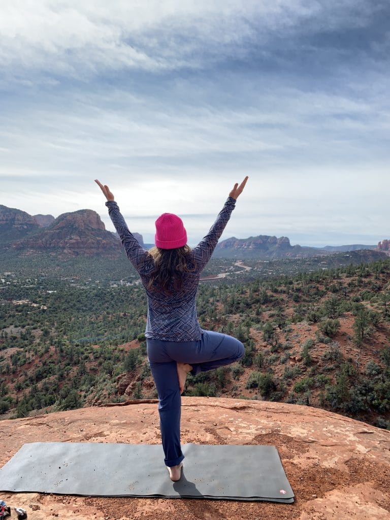 Ashley doing a pilates pose on a yoga mat out in a desert landscape.