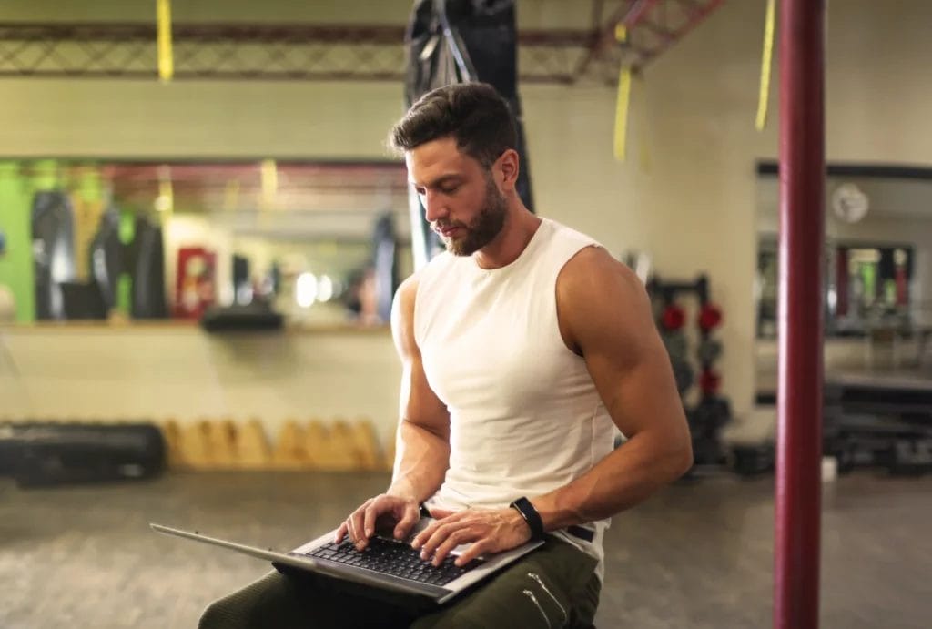 A personal trainer using a laptop in the gym