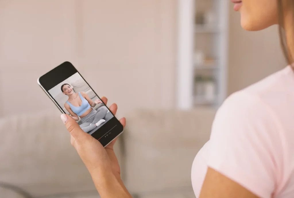 An up-close look at someone watching videos of a virtual trainer on their smart phone