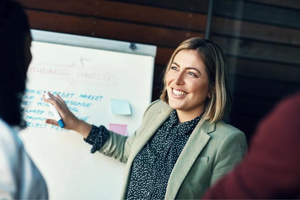 Life coach presenting business strategy to an audience with a white board.