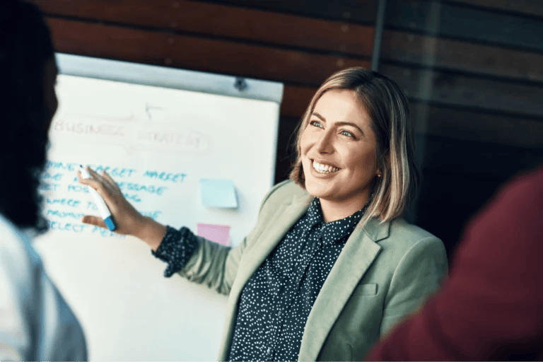 Life coach presenting business strategy to an audience with a white board.