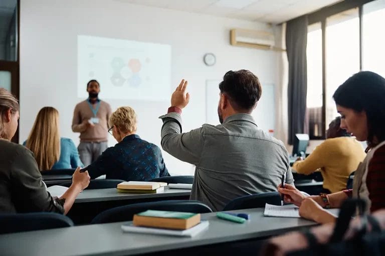 Consultant in an in-person class raising their hand