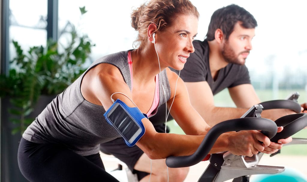 A pin instructor is listening to a podcast in her headphones while practicing on a stationary bike.