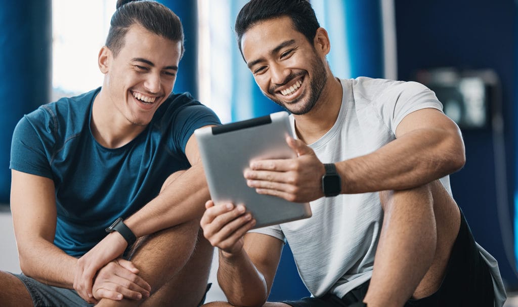 A trainer and his client are smiling as they look at their client's training plan for the upcoming year.