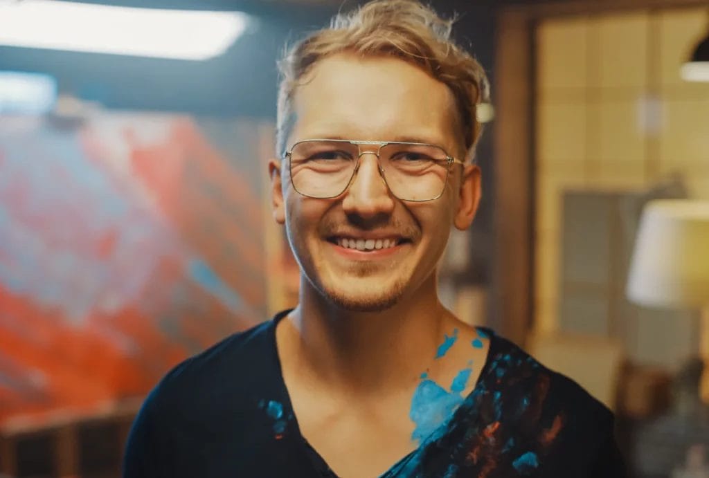 Smiling artist covered in paint in a studio