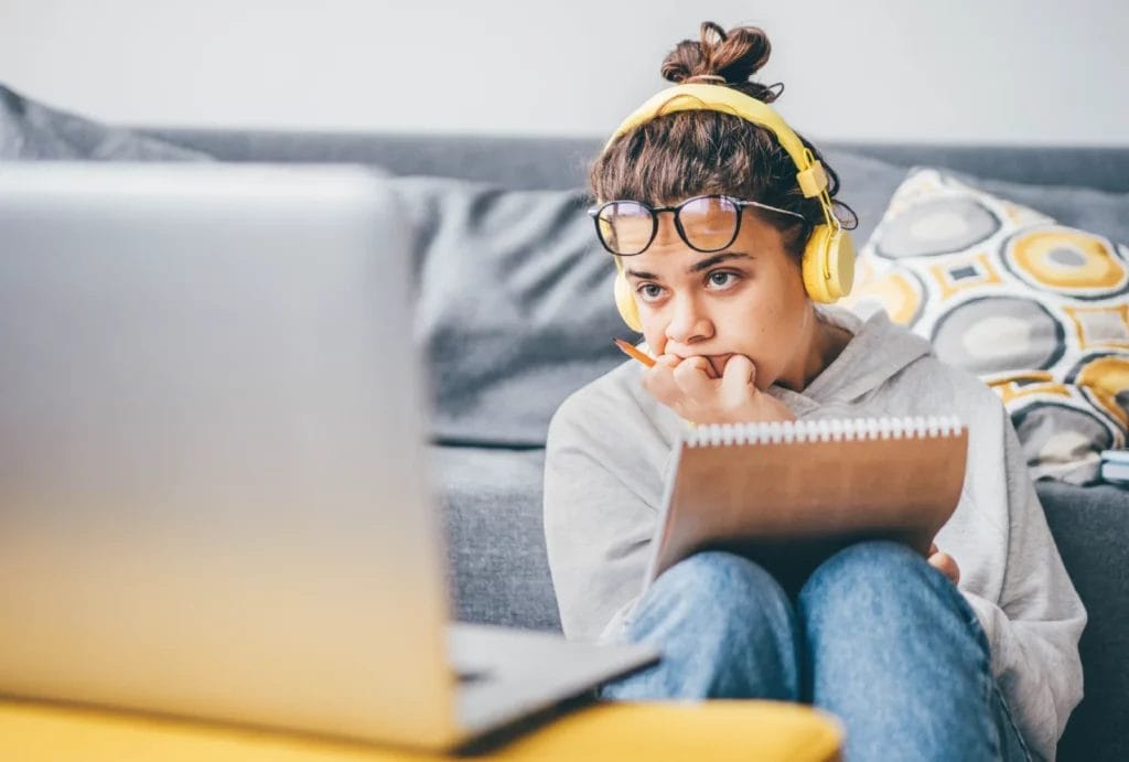 Woman working at home looking at laptop screen in frustration.