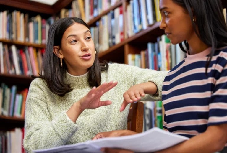 Tutor discusses homework with a student in a library