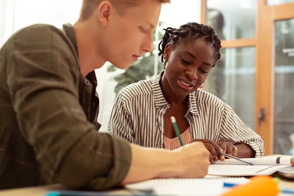 Private tutor in lesson with student writing on paper