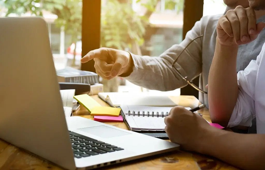 Private tutor in a lesson with computer, notebooks, and writing tools.