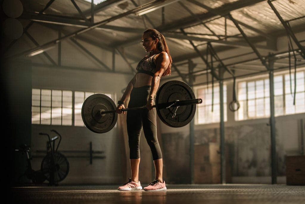 an athlete holds a deadlift in a gym.