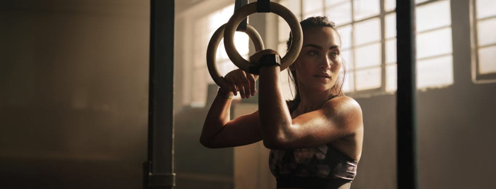 an athlete leans against rings during a workout.