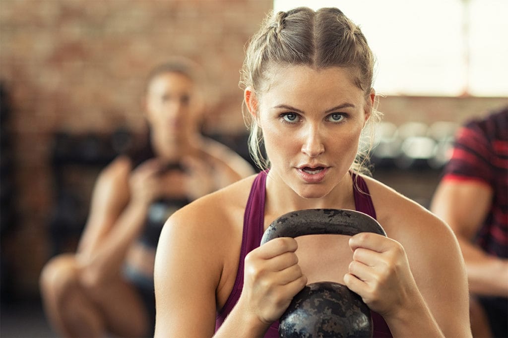 a woman leads a kettlebell fitness class.