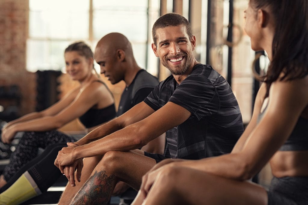 A man smiles at a friend in a fitness class.