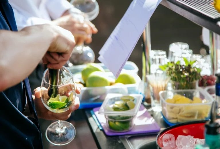Outdoor bartender preparing mojitos surrounded by ingredients