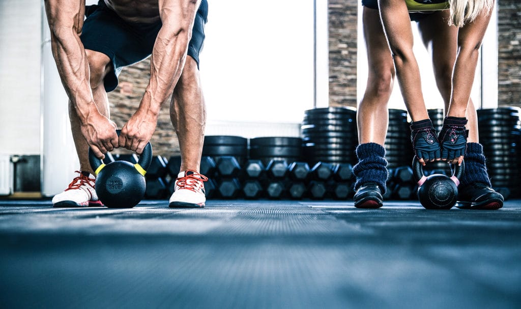 A personal trainer is showing a client how to train with a kettleball.