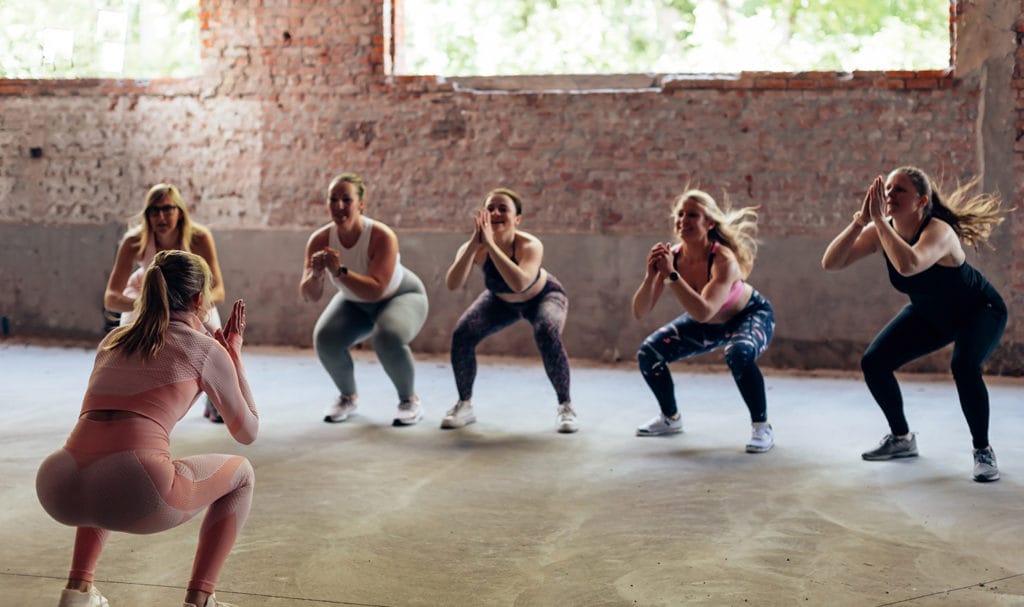 A group personal trainer is leading students through a routine with squats.