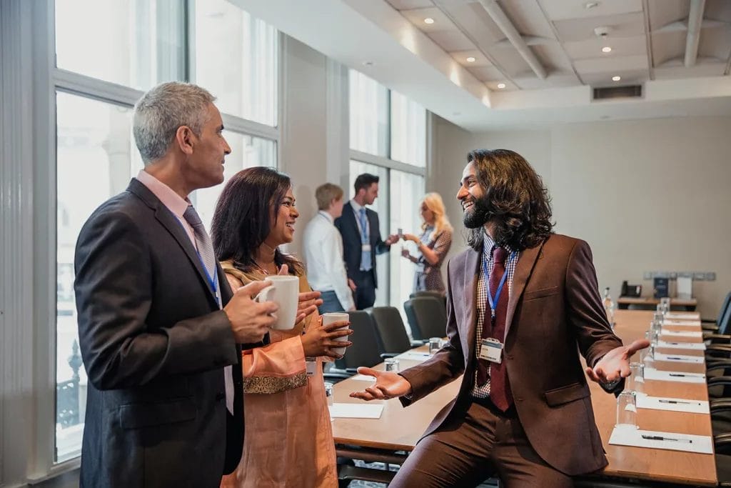 Three people at a business related event collaborating and speaking together