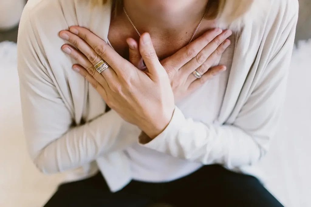 A close up of a woman's torso who is holding her arms crossed on her chest.