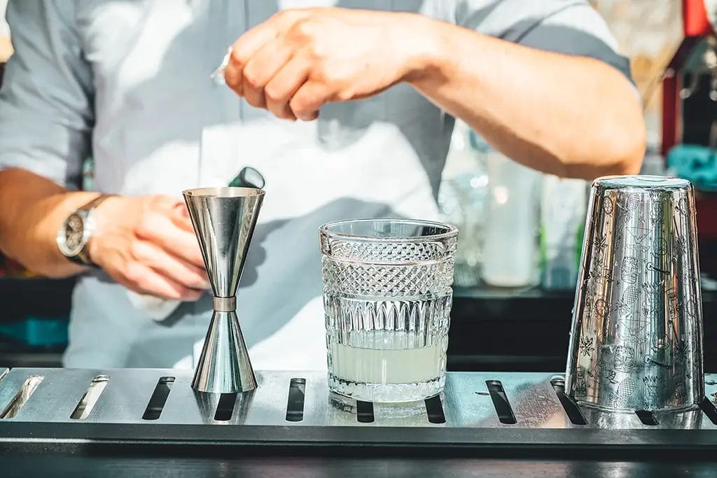 A bartender making a cocktail at an outdoor bar.