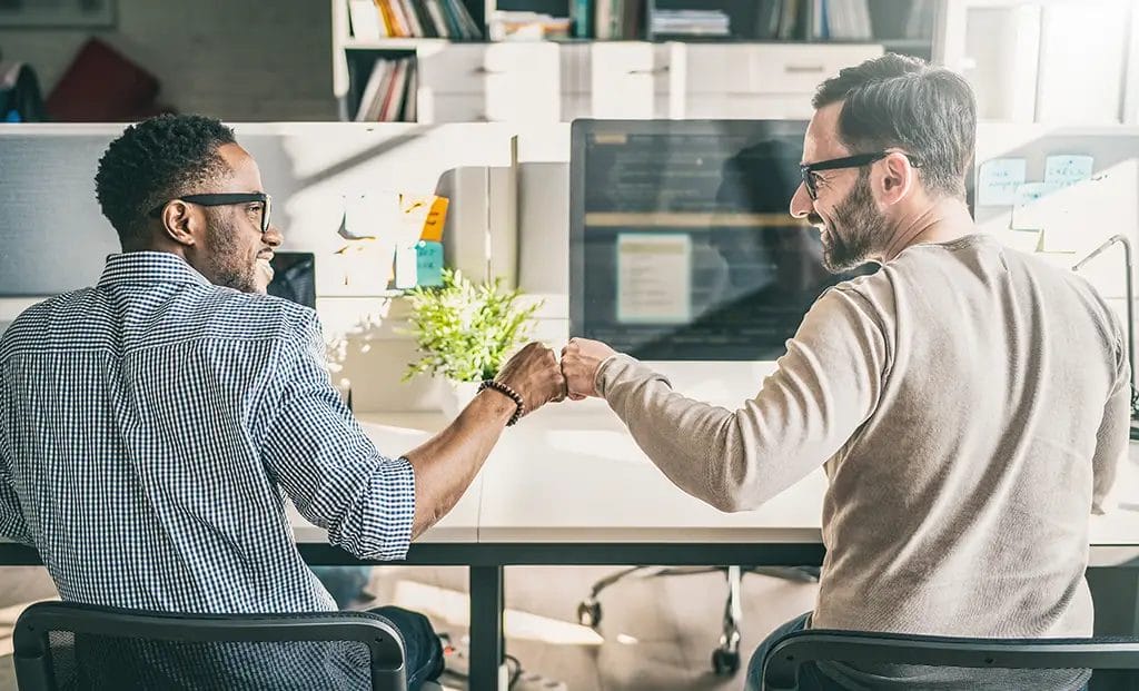 Two people giving each other a fist bump to show positive rapport