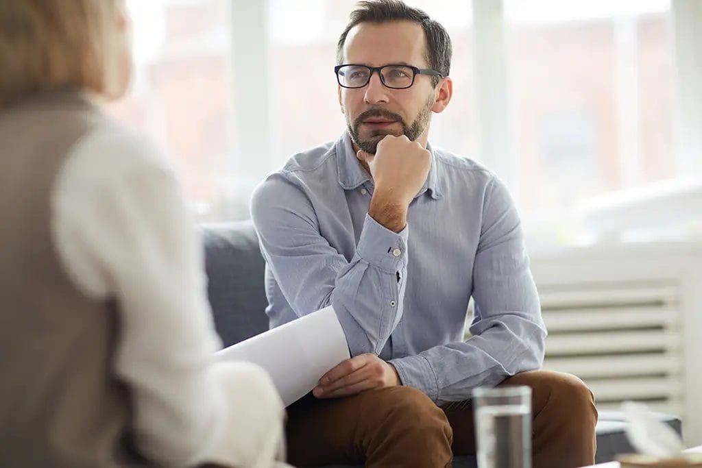 Person sitting across from another actively listening to a conversation.