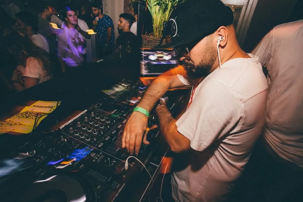 A DJ at a turntable performing at a small indoor party.