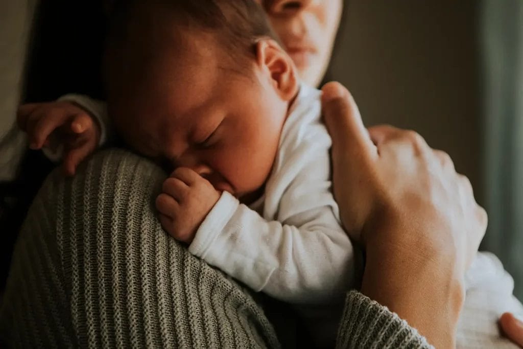 Close up of newborn baby cuddling mother