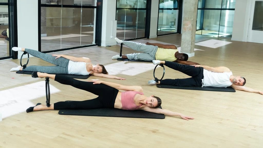 A group doing pilates on the floor of a gym.