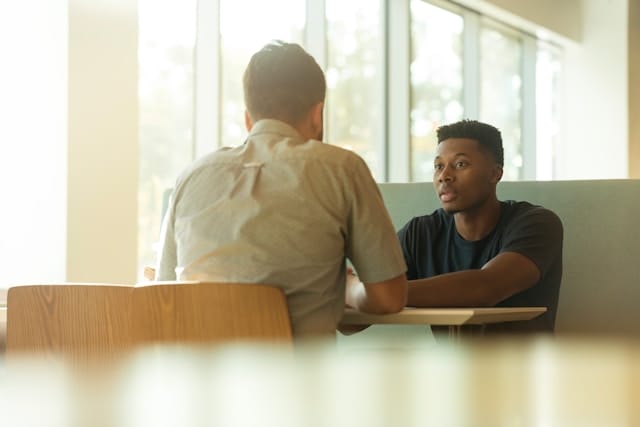 A coach speaking to a client at a table