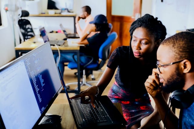 woman offers advice to a client next to a computer