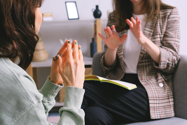 two women sit across from one another in conversation