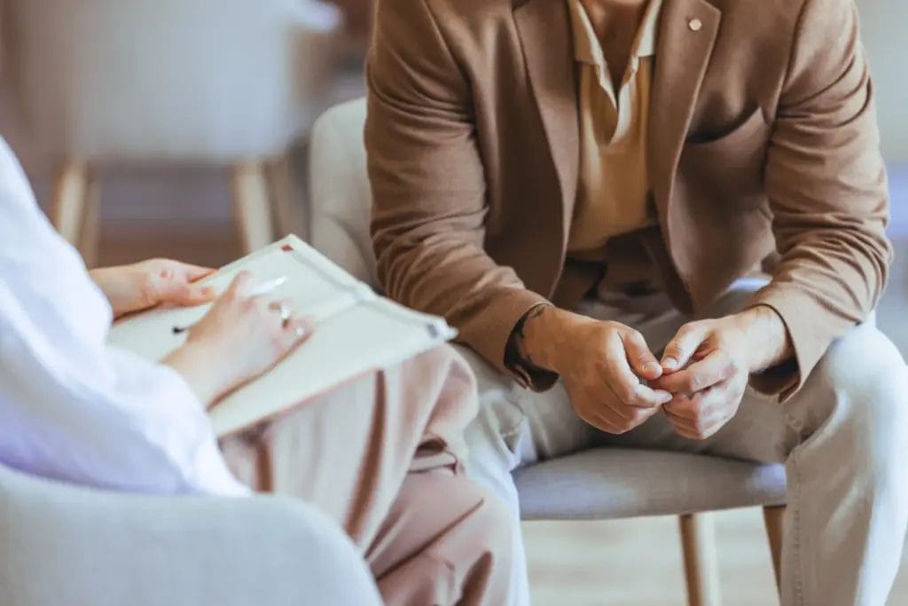A close-up shot of a life coach and their clients' hands during a session, with the life coach taking notes in a notebook.