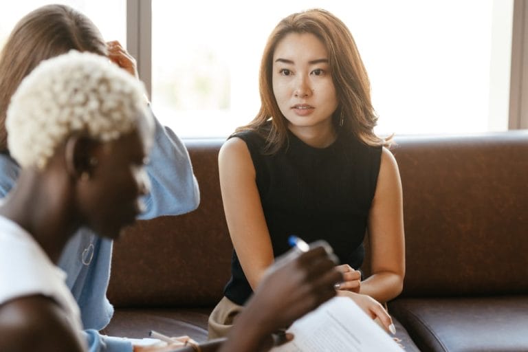 a young woman looks concerned while talking to colleagues