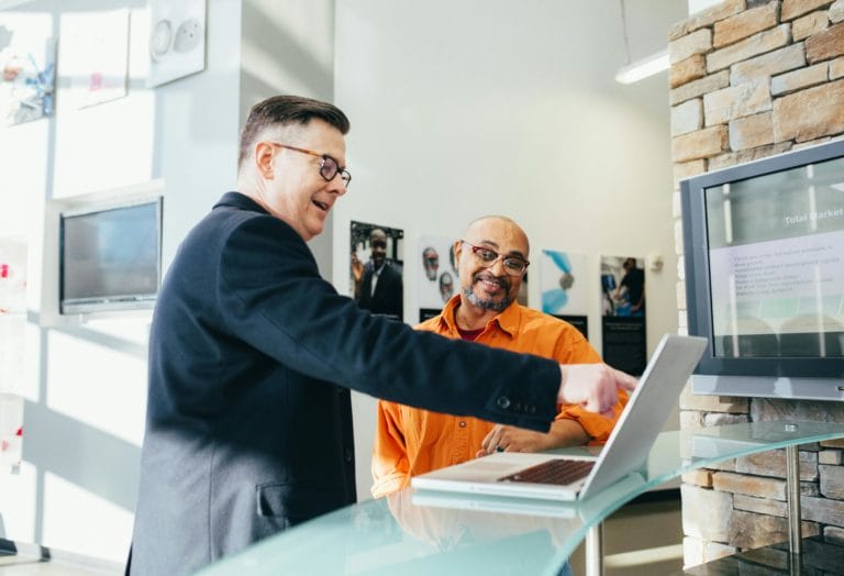 man points to computer in business setting