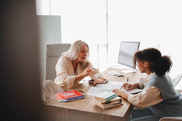 two women educators engaged in conversation at a desk