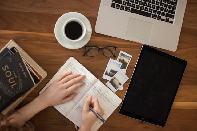 person holding ballpoint pen writing in notebook