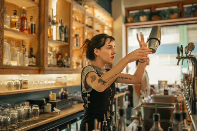 A bartender flipping a drink shaker in the air.