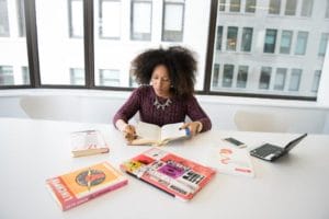 woman sits at a desk surrounded by books