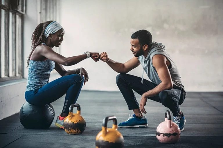 A personal trainer fist bumps a client.