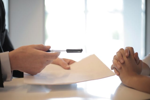 a document and pen extended to a client