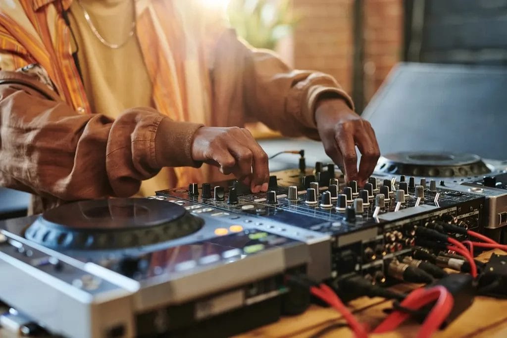 A DJ turning knobs on their equipment in a studio.