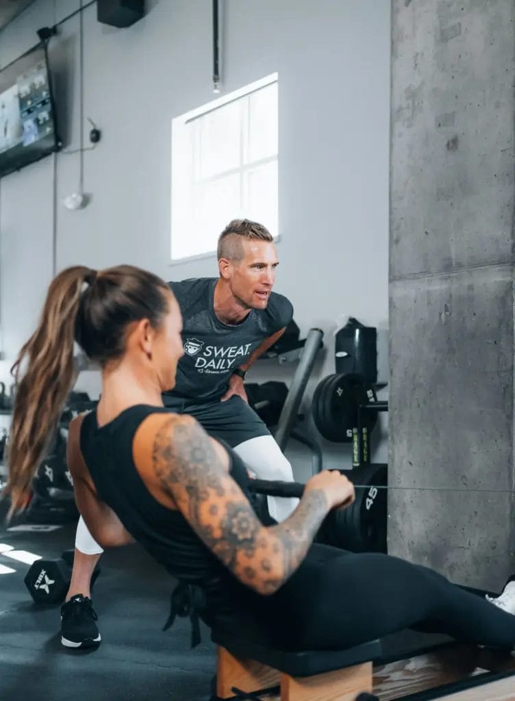 Trainer coaching client on row machine
