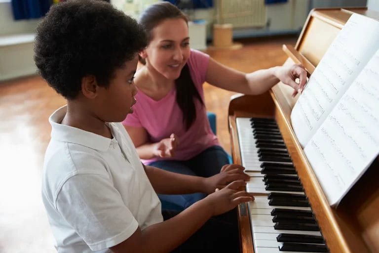 A woman teaches a young boy how to play piano.