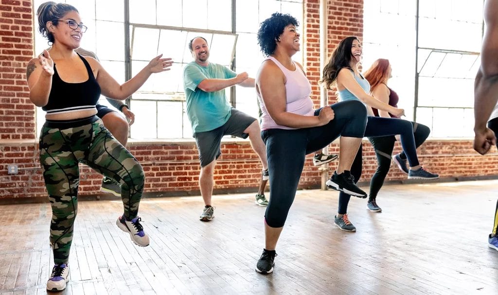 Happy Zumba students following a routine in an indoor class setting.
