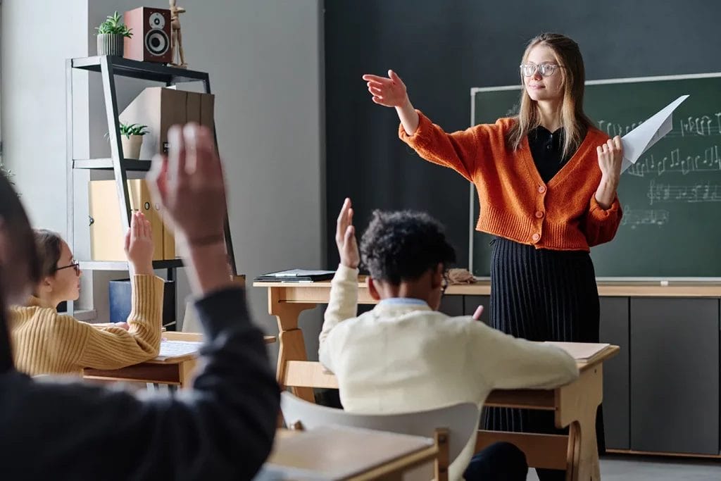 Music teacher in classroom with student raising hand