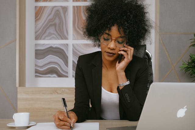 a business woman takes a call in front of an open laptop