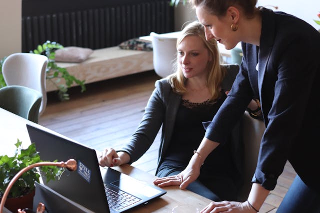 a business consultant and a client talk in front of a desk