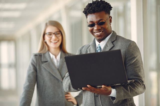 two consultants smiling in front of a computer