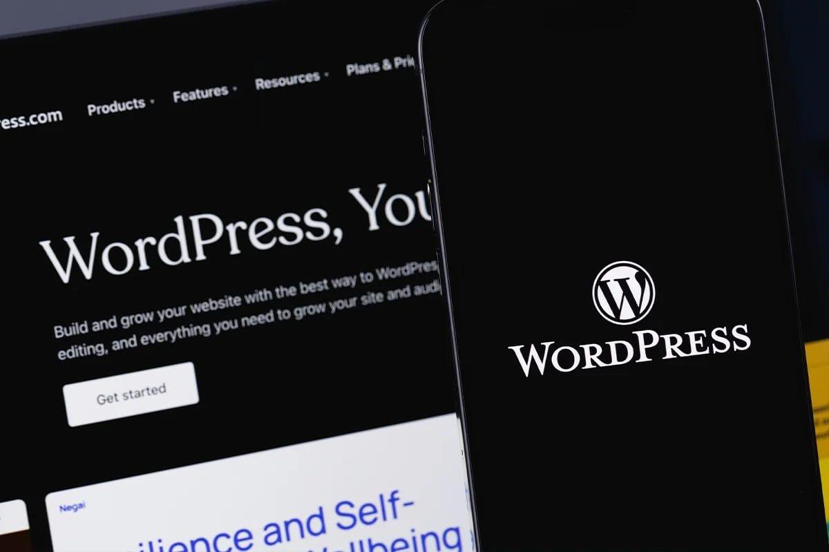 Wordpress logo on a black background, displayed on a smartphone and desktop screen.